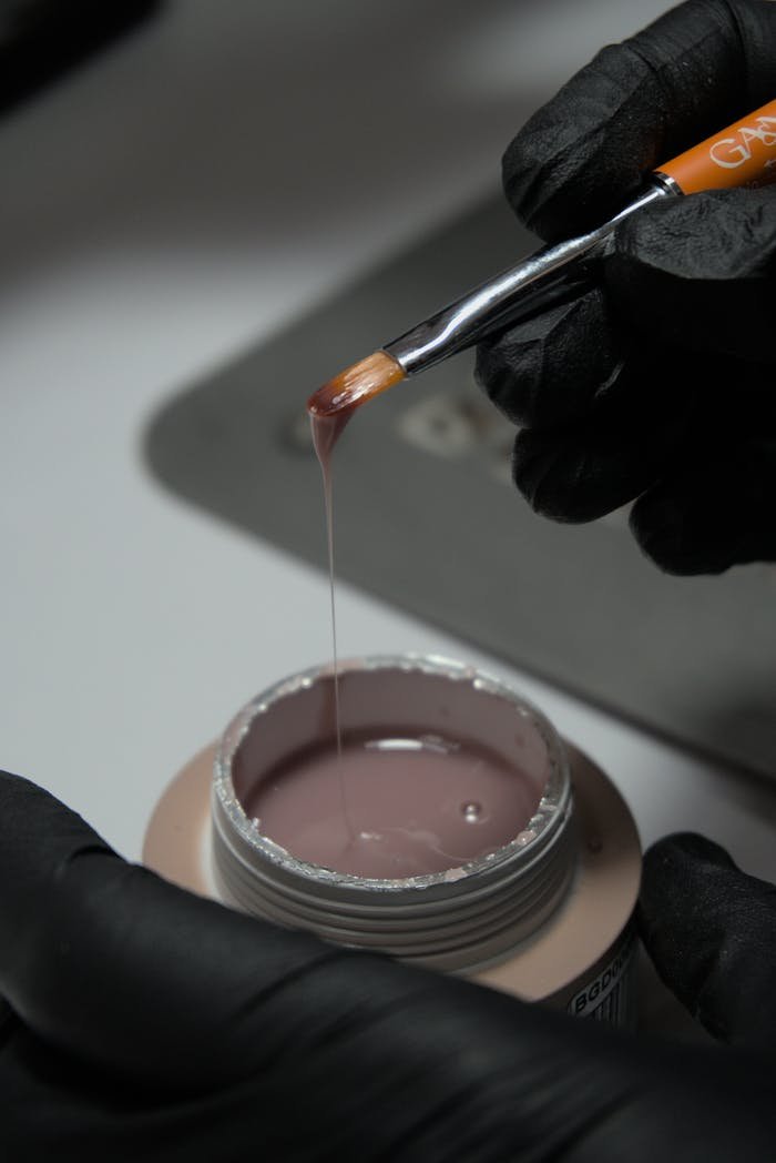 Detailed view of nail gel application with brush, showcasing beauty and care.